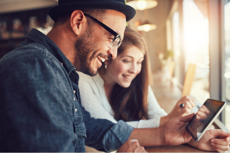 Male and female sitting behind a tablet