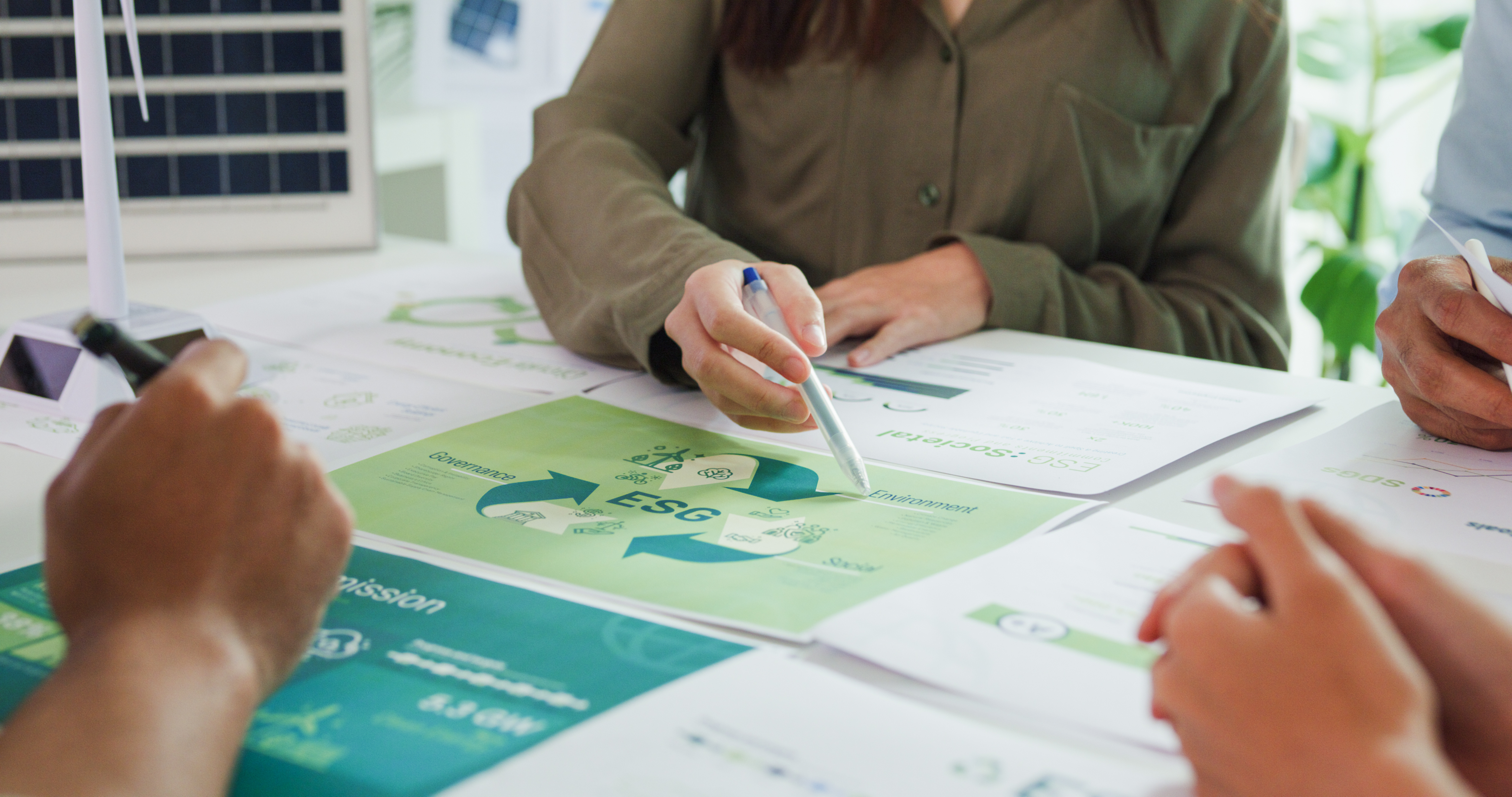 People collaborating on Kiwa's ESG reports with charts and documents on a table, focusing on sustainable development strategies