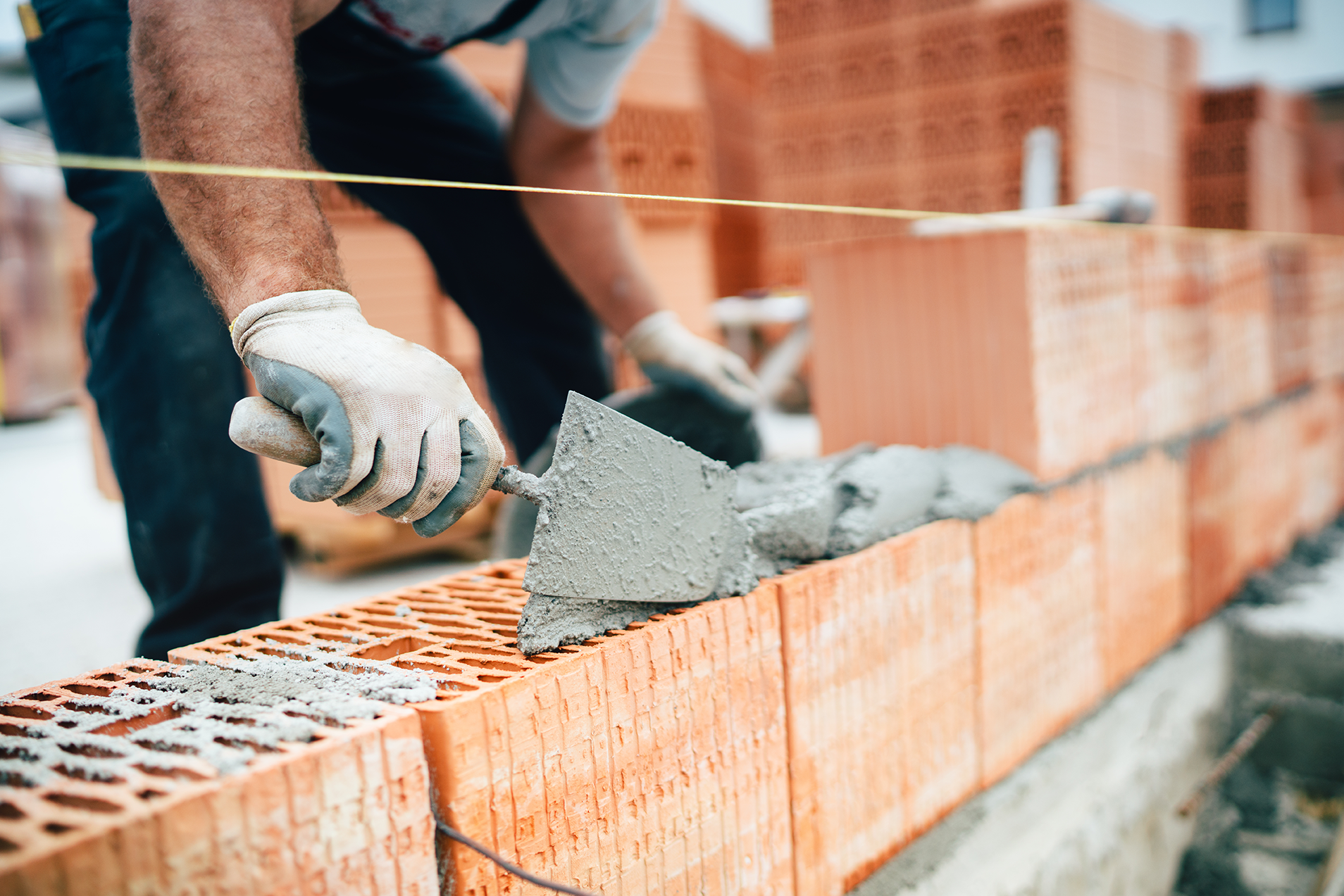 Construction worker laying bricks and applying mortar with a trowel on a brick wall