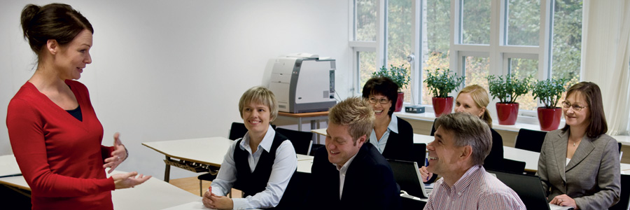 Female Kiwa trainerleading a business training session with engaged adult learners in a classroom setting