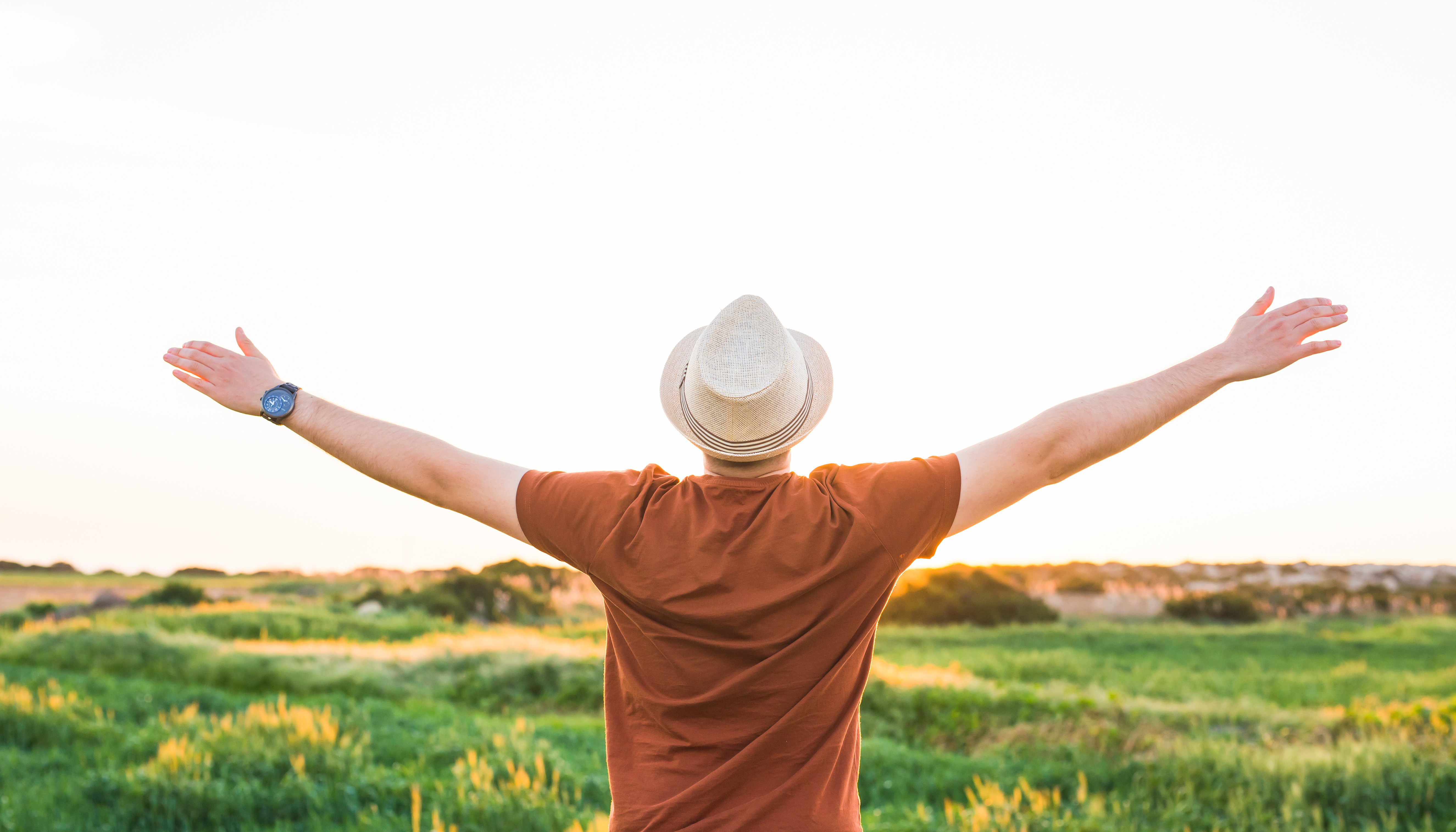 man standing in a filed with open arms