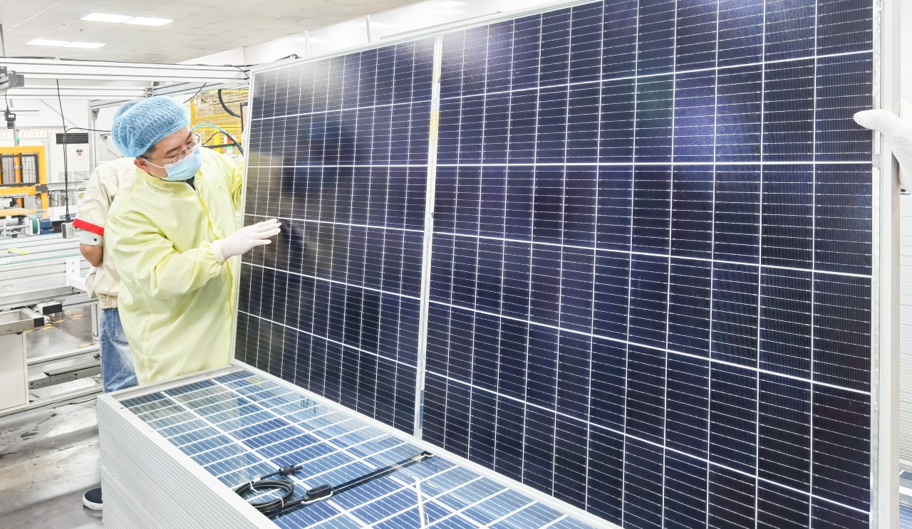 Technician inspecting solar panels in a clean energy manufacturing facility