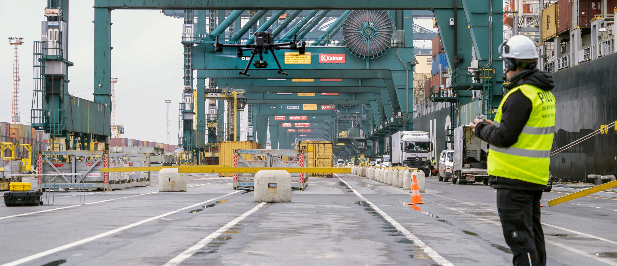 Kiwa drone pilot operating a drone in a busy shipping port with cranes and cargo containers, enhancing logistics and security operations