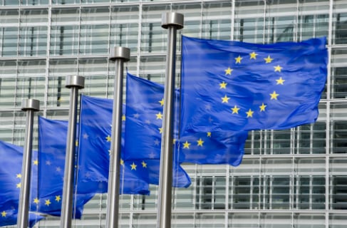 European Union flags flying in front of a modern glass building