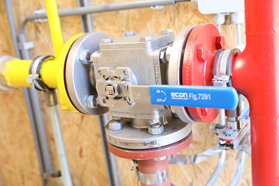 Industrial valve with a blue handle labeled "econ Fig.7291" installed on piping system