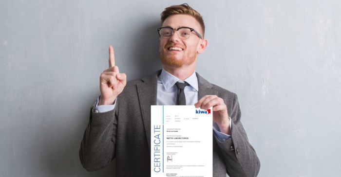 Kiwa employee dressed up in a suite holding a Kiwa certificate