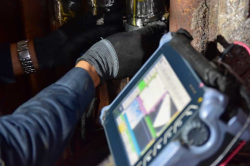 Person som utför ultraljudsundersökning på metallrör med specialutrustning.