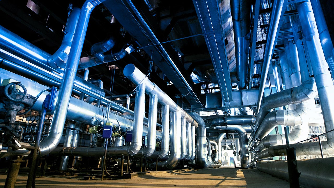 Ett rum fullt med olika slags rörledningar i en industri. 