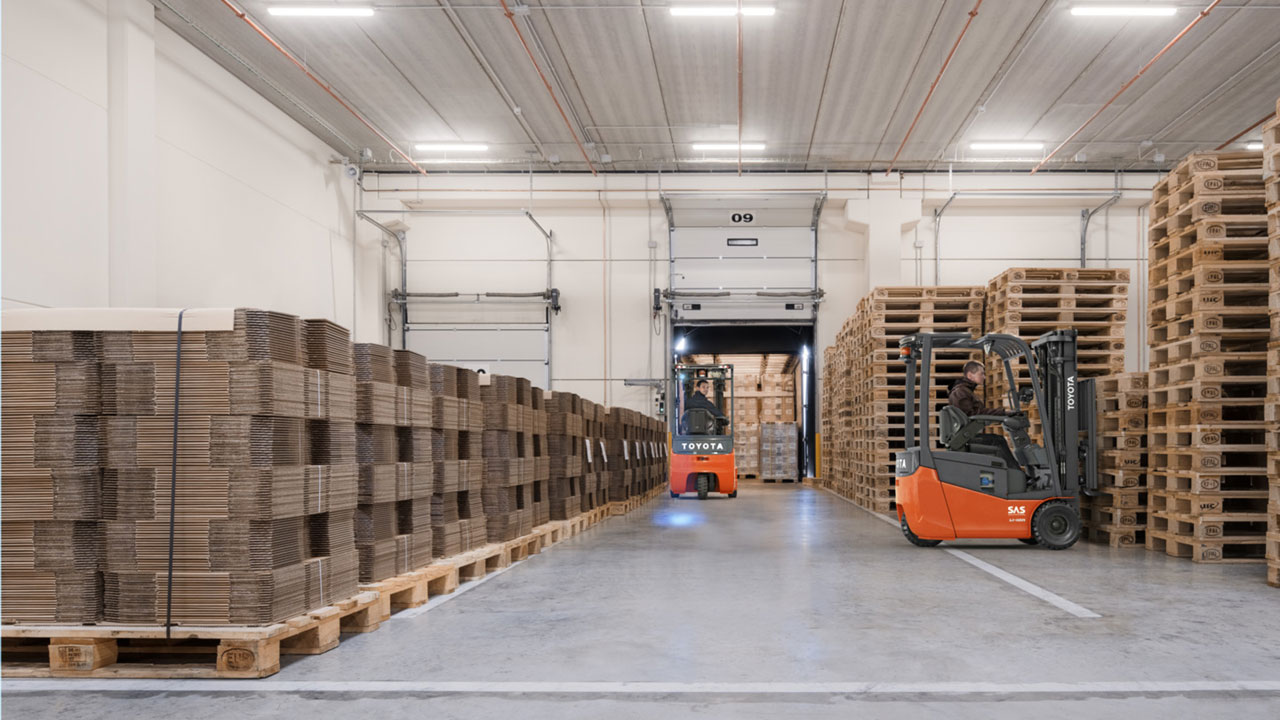 Två truckförare arbetar i ett lager och lastar en lastbil. 