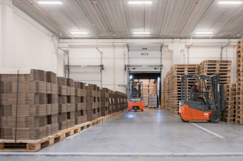 Två truckförare arbetar i ett lager och lastar en lastbil.