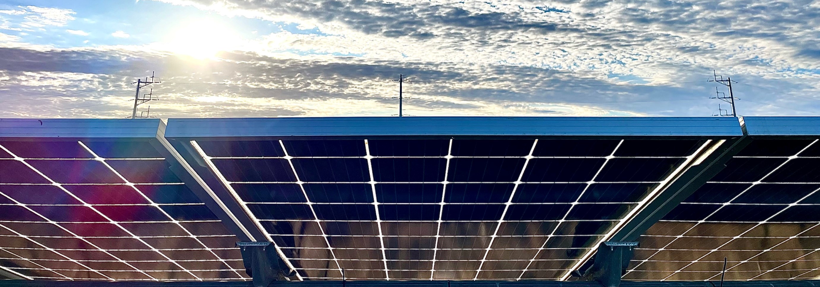 Solar panels on a rooftop under a bright sky with scattered clouds